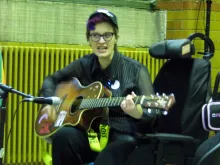 Photograph of Dennis Queen singing and playing acoustic guitar in the People's History Museum